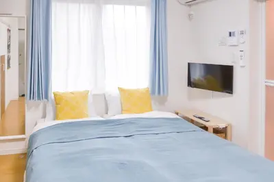 a bedroom with a bed with blue sheets and yellow pillows at Triphome Tateishi New open/2 single beds/big table/300M WiFi in Tokyo