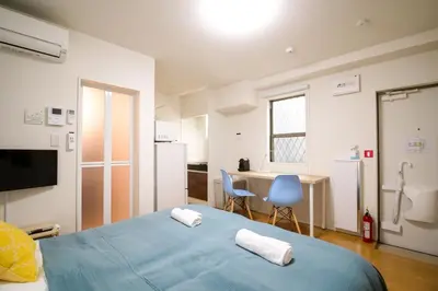 a bedroom with a blue bed and a kitchen at Triphome Tateishi New open/2 single beds/big table/300M WiFi in Tokyo