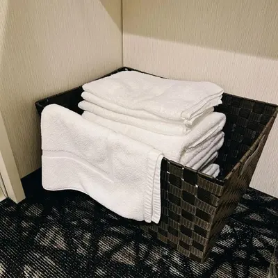 a pile of white towels on a rack in a room at AYA Hotel in Tokyo