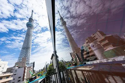 two towers are reflected in the windows of a building at La Krasse Skytree - Vacation STAY 12839 in Tokyo