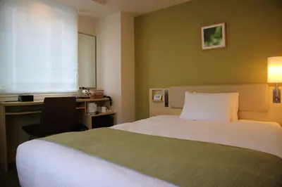 a bedroom with a bed and a desk and a window at Smile Hotel Shinagawa Sengakuji Ekimae in Tokyo