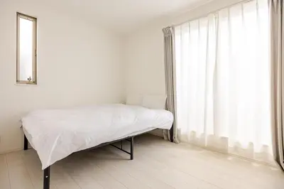 a white bedroom with a bed and a window at Senjyu House in Tokyo