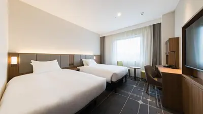 a hotel room with two beds and a flat screen tv at JR-East Hotel Mets Mejiro in Tokyo