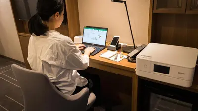 a woman sitting at a desk with a laptop computer at JR-East Hotel Mets Mejiro in Tokyo