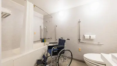 a wheelchair in a bathroom with a toilet and a sink at JR-East Hotel Mets Mejiro in Tokyo