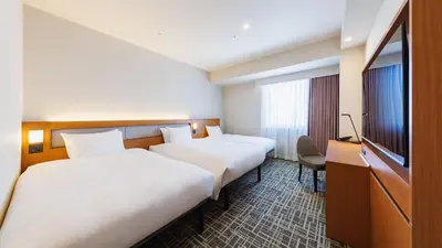 a hotel room with two beds and a flat screen tv at JR-East Hotel Mets Komagome in Tokyo