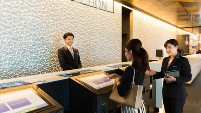 a man and two women standing in front of a counter at JR East Hotel Mets Premier Akihabara in Tokyo