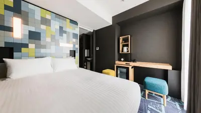 a bedroom with a white bed and a blue chair at JR East Hotel Mets Premier Akihabara in Tokyo