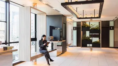 a woman sitting on a bench in a room with windows at JR East Hotel Mets Premier Gotanda in Tokyo