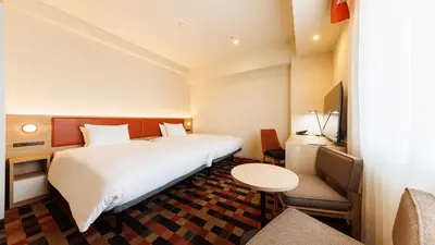 a hotel room with a bed and a table and chairs at JR-East Hotel Mets Koenji in Tokyo