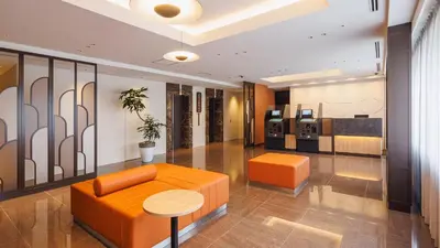 a lobby with an orange couch and a table at JR-East Hotel Mets Koenji in Tokyo