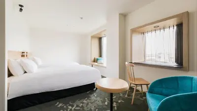 a bedroom with a white bed and a blue chair at JR East Hotel Mets Premier Tokyo Bay Shinkiba in Tokyo