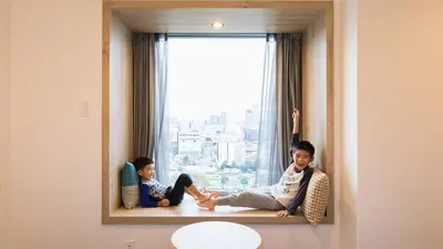 two children sitting on a window sill in front of a window at JR East Hotel Mets Premier Tokyo Bay Shinkiba in Tokyo
