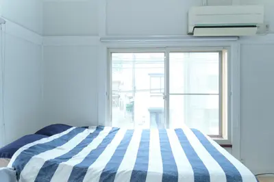 a blue and white striped bed in a room with a window at Minami-Shinagawa House by Tranova in Tokyo