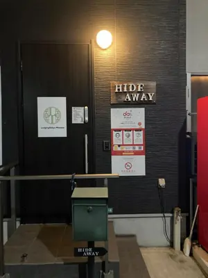 a hallway with a huddle away sign on a wall at Hostel LodgingToyko Minowa in Tokyo