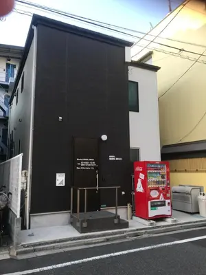a black building with a red door on a street at Hostel LodgingToyko Minowa in Tokyo