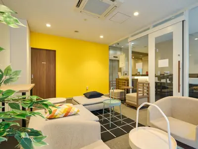 a living room with yellow walls and couches at Tabist Ginza in Tokyo