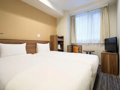 a hotel room with two beds and a television at Tabist Ginza in Tokyo