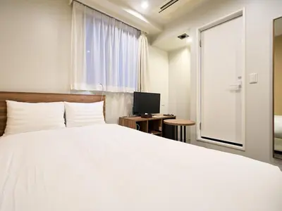a bedroom with a white bed and a television at Tabist Ginza in Tokyo