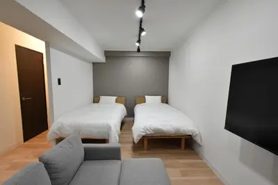 a room with two beds and a couch and a flat screen tv at LUCKY house43 in Tokyo