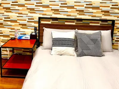 a bedroom with a white bed with a wooden wall at tani house in Tokyo