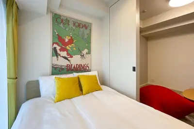 a bedroom with a white bed with yellow pillows at \u30d1\u30fc\u30af\u30a2\u30af\u30b7\u30b9\u672c\u6240\u543e\u59bb\u6a4b\u30b5\u30a6\u30b9\u30ec\u30b8\u30c7\u30f3\u30b9 in Tokyo