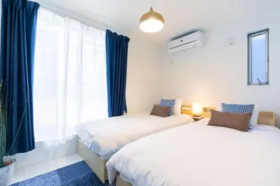 two beds in a bedroom with blue curtains and a window at SHIBUYA TOKYO in Tokyo