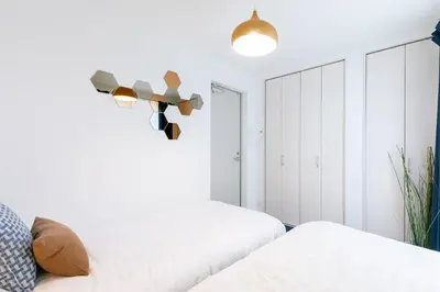 a white bedroom with two beds and a mirror at SHIBUYA TOKYO in Tokyo