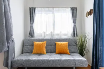 a gray couch with two orange pillows in front of a window at SHIBUYA TOKYO in Tokyo