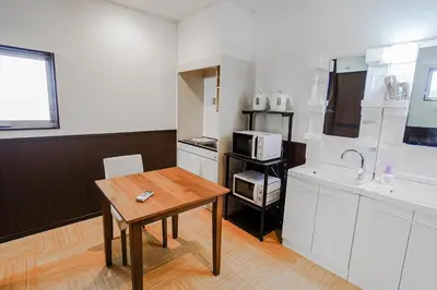 a kitchen with white cabinets and a table in it at SAMURAI STAY \u6d17\u8db3\u6c60-male only \u7537\u6027\u5c02\u7528 in Tokyo