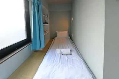 a small bed in a room with a window at \u7121\u6599wi-fi JING HOUSE \u79cb\u8449\u539f \u96fb\u52d5\u81ea\u8ee2\u8eca\u30ec\u30f3\u30bf\u30eb in Tokyo