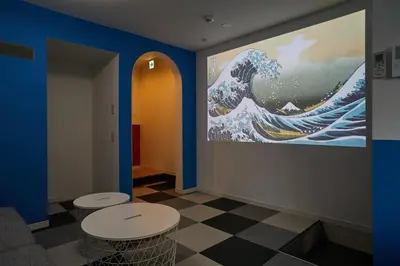 a room with two stools and a painting of the tsunami at Designer's Villa in Shinjuku-ku Shin-Okubo sta 6 min walk F in Tokyo