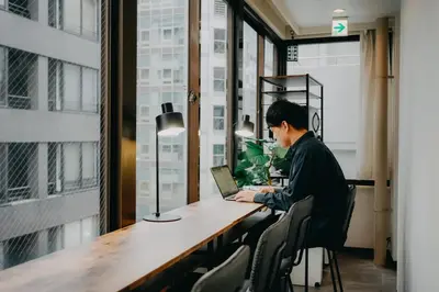 a man sitting at a desk with a laptop at unito light SHIMBASHI in Tokyo