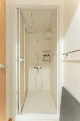 a white bathroom with a shower in a room at unito light SHIMBASHI in Tokyo