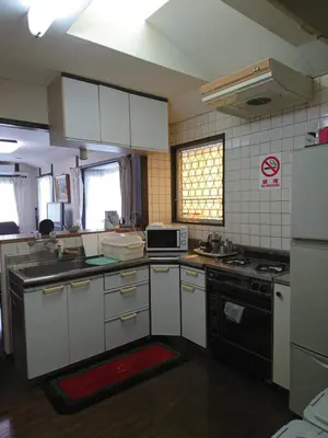 a kitchen with white cabinets and a stove top oven at Homestay Intimo Amigo in Tokyo
