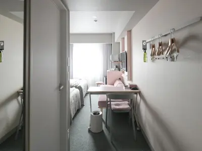 a small room with a sink and a bed at Vessel Inn Takadanobaba Station in Tokyo