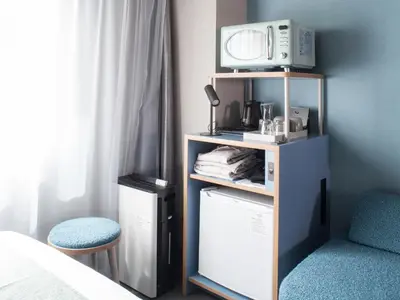 a room with a mirror and a microwave on a shelf at Vessel Inn Takadanobaba Station in Tokyo