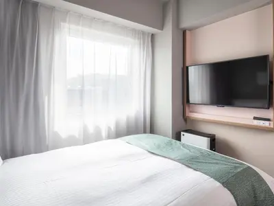 a bedroom with a bed and a flat screen tv at Vessel Inn Takadanobaba Station in Tokyo