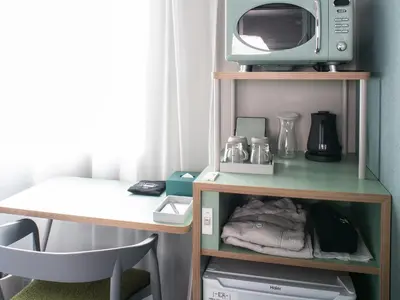 a kitchen with a table and a microwave on a shelf at Vessel Inn Takadanobaba Station in Tokyo