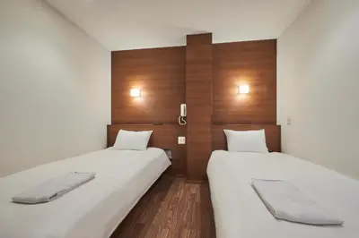 two beds in a small room with wooden walls at \u82e5\u6d45\u8349\u548c\u5fc3\u30db\u30c6\u30eb in Tokyo