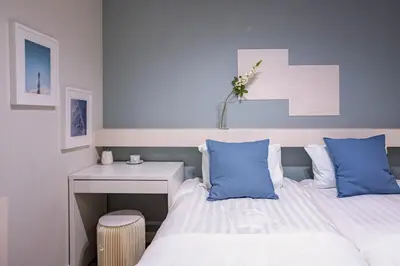 a bedroom with a bed with blue pillows and a desk at Asakusa YOSHII Designer Hotel in Tokyo