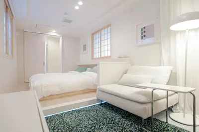 a white bedroom with a bed and a chair at Asakusa YOSHII Designer Hotel in Tokyo