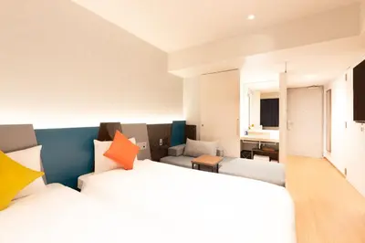 a hotel room with two beds and a couch at karaksa hotel colors Tokyo Yaesu in Tokyo