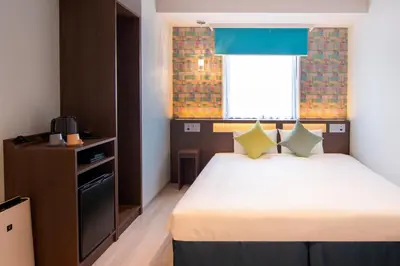 a small bedroom with a bed and a window at karaksa hotel colors Tokyo Yaesu in Tokyo