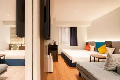 a hotel room with two beds and a couch at karaksa hotel colors Tokyo Yaesu in Tokyo