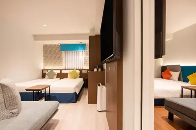 a hotel room with two beds and a couch at karaksa hotel colors Tokyo Yaesu in Tokyo