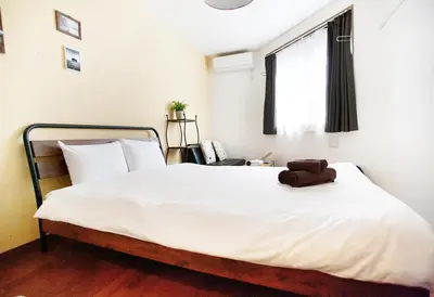 a bedroom with a large white bed with a bag on it at Ustay Kitakoiwa in Tokyo