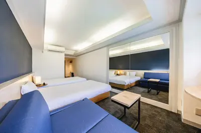 a hotel room with two beds and a couch at L stay & grow Harumi in Tokyo