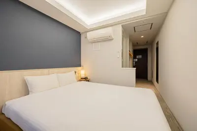 a bedroom with a white bed and a blue wall at L stay & grow Harumi in Tokyo