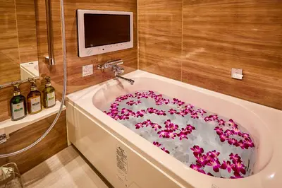 a bathroom with a tub filled with pink flowers at Petit Bali Ikebukuro in Tokyo